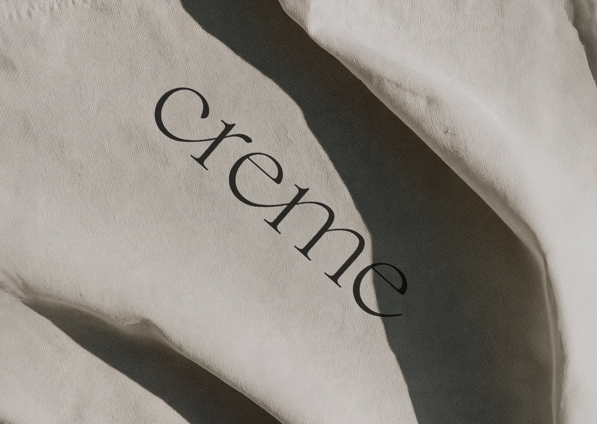 Close-up of cream fabric printed with the word “creme” in Chiffon typography under strong natural light.