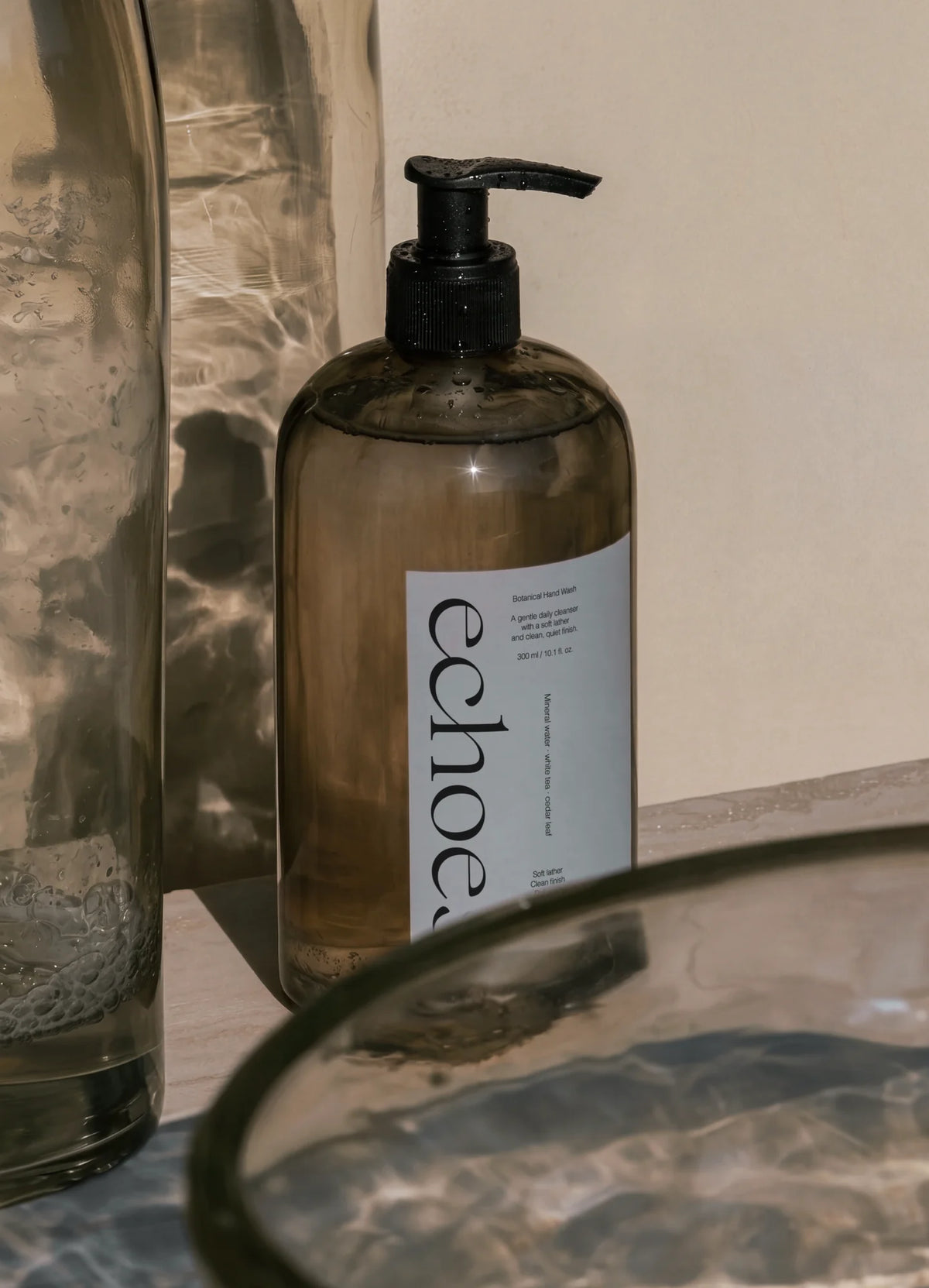 Amber pump bottle with Echoes soap branding and Chiffon typography in a minimal bathroom setting.