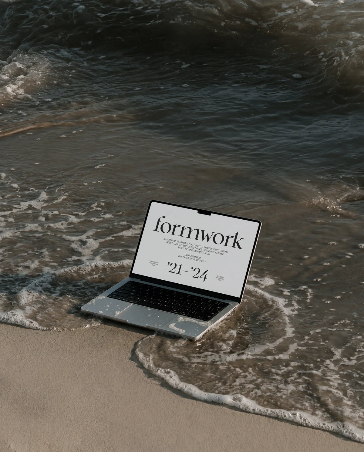 Laptop displaying Formwork editorial typography in Chiffon, positioned at the edge of the sea.