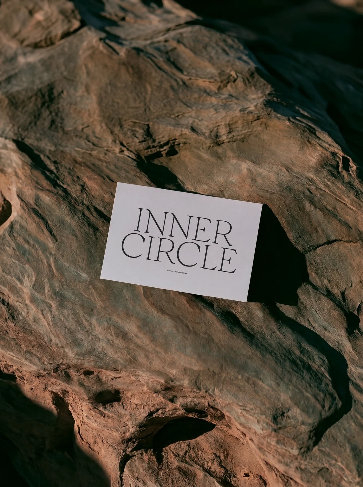White editorial card reading “Inner Circle” in Velour Raw, photographed on textured dark rock.